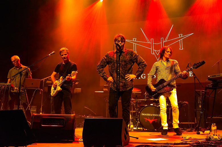 "Images in Vogue" band on stage with dramatic lighting. Lead singer singing into microphone with keyboard player, guitar, and bass player visible.